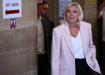 Marine Le Pen, in a pink blazer and white shirt, arrives at court.
