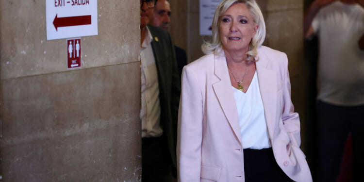 Marine Le Pen, in a pink blazer and white shirt, arrives at court.