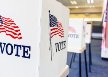 Rows of empty voting booths fill a bright civic center.