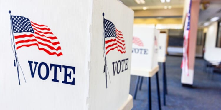 Rows of empty voting booths fill a bright civic center.