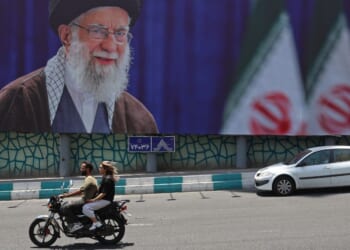 Motorists ride past a giant billboard bearing a picture of Iran's late supreme leader Ayatollah Ali Khamenei Thursday ahead of his funeral in Tehran.