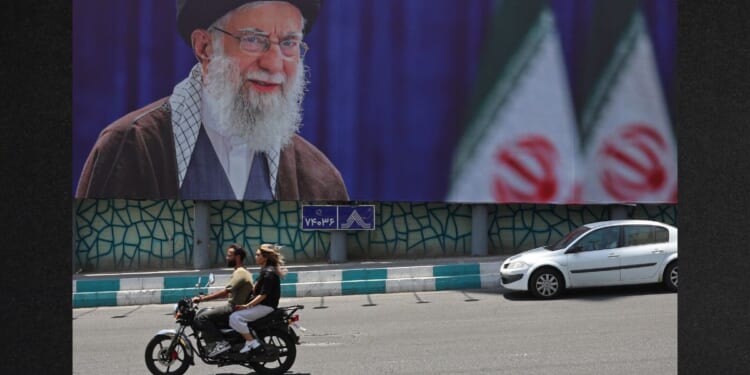 Motorists ride past a giant billboard bearing a picture of Iran's late supreme leader Ayatollah Ali Khamenei Thursday ahead of his funeral in Tehran.
