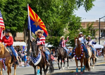 A female participant riding a horse while holding a flag in Prescott, Arizona, on July 3, 2021.