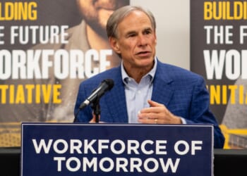 Gov. Greg Abbott in a blue blazer speaks at a podium labeled “Workforce of Tomorrow,” with banners behind him reading “Building the Future Workforce Initiative.”