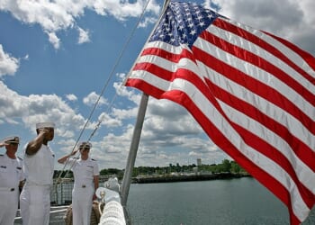 Lt. Paul Brawley, Seaman Deville Warner, and ENS Christopher Bongard salute the flag