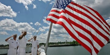 Lt. Paul Brawley, Seaman Deville Warner, and ENS Christopher Bongard salute the flag