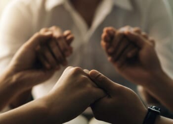 A group of people holding hands praying.