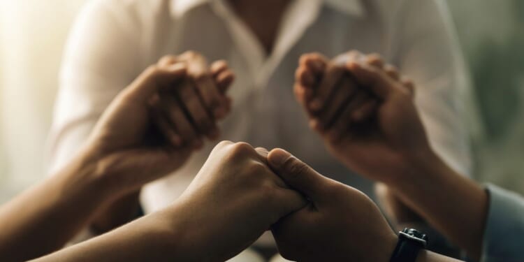 A group of people holding hands praying.