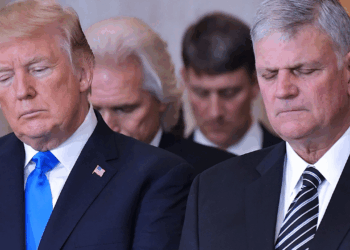 Donald Trump stands next to Franklin Graham in the US Capitol Rotunda, both bowing their heads in prayer.