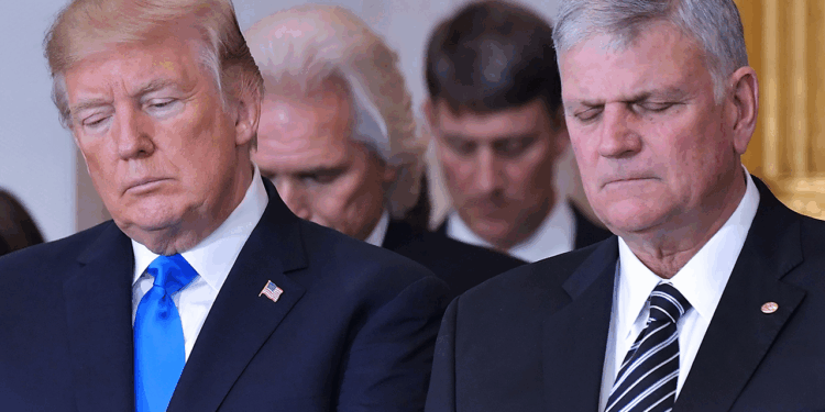 Donald Trump stands next to Franklin Graham in the US Capitol Rotunda, both bowing their heads in prayer.