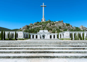 The Basilica of the Holy Cross at the Valley of Cuelgamuros, with cross rising high against a perfect blue sky.
