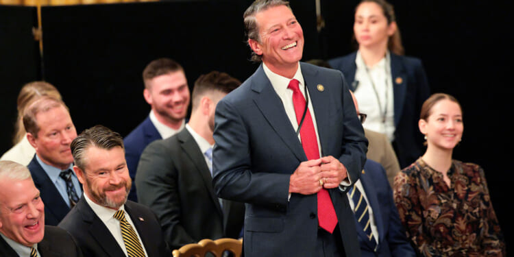 U.S. Rep. Ronny Jackson (R-TX) March 20, 2026 stands laughing amid a group of seated individuals.
