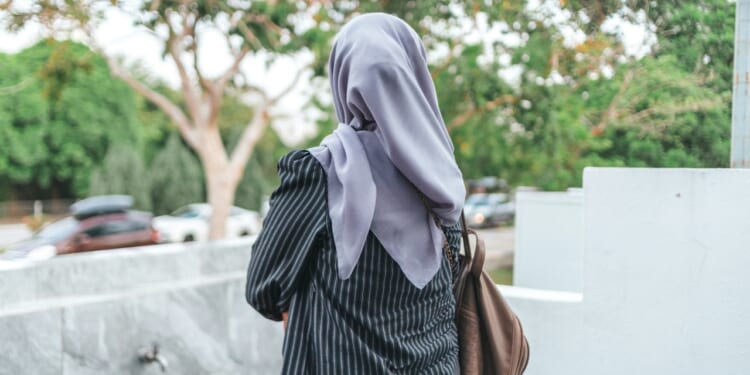 Woman wearing a hijab walks away from camera.
