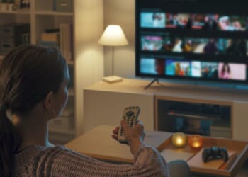 A young woman turns on the television in her living room.