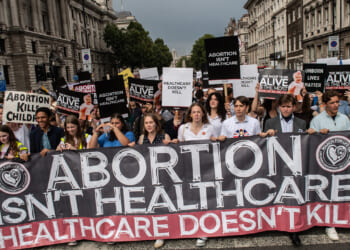 Pro-life protesters holding a sign: "Abortion Isn't Healthcare. Healthcare doesn't kill."