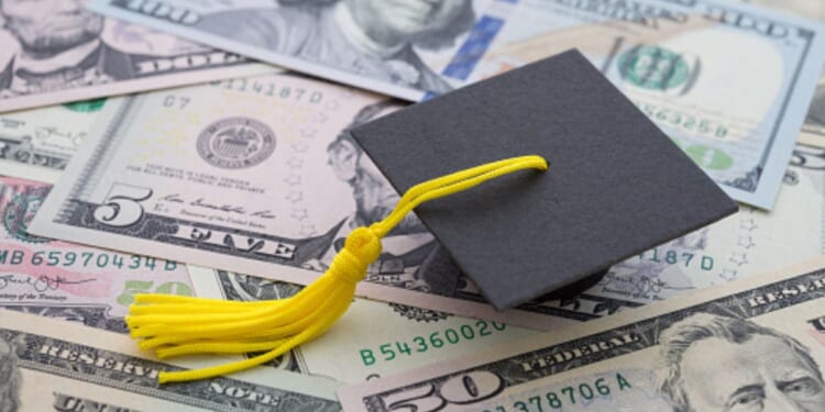 A graduation cap sits on a pile of money.