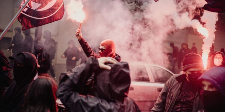 A person is holding a red smoke bomb during an anti-fascist demonstration held to mark the 13th anniversary of the death in 2013 of activist Clement Meric in Paris, France, on June 6, 2026.