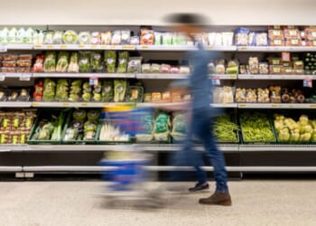 A man walks through a grocery store aisle.