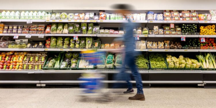 A man walks through a grocery store aisle.