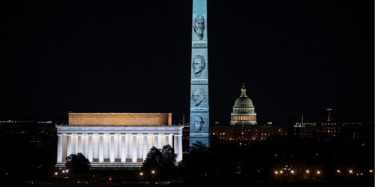 The Washington Monument stands illuminated with Founding Fathers’ faces on January 3, 2026.