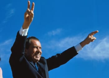Richard Nixon gives two-armed victory salute