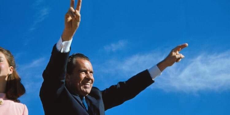 Richard Nixon gives two-armed victory salute
