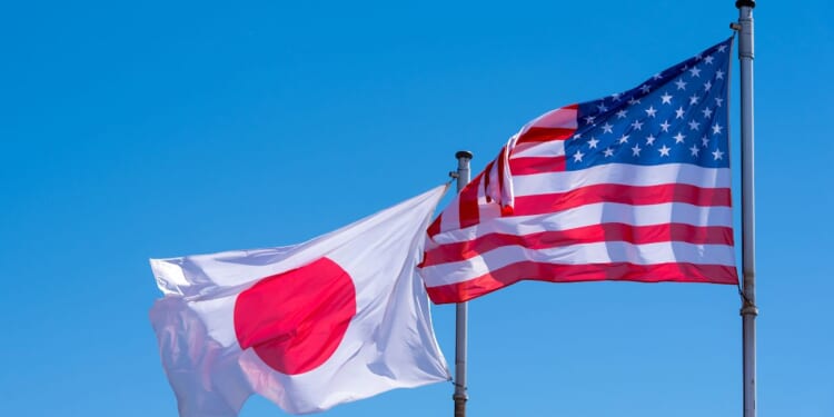 American and Japanese flags waving against a blue sky.