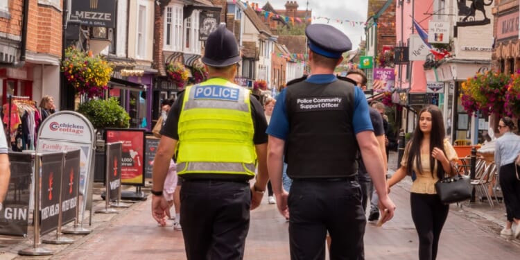 A policeman and a police community support officer walking down a busy street in Canterbury, Kent, United Kingdom, on Aug. 7, 2021.