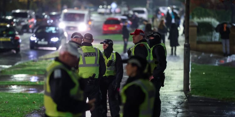 Police officers patrol the street as fireworks go off in the distance on Nov. 5, 2025, in Edinburgh, Scotland.