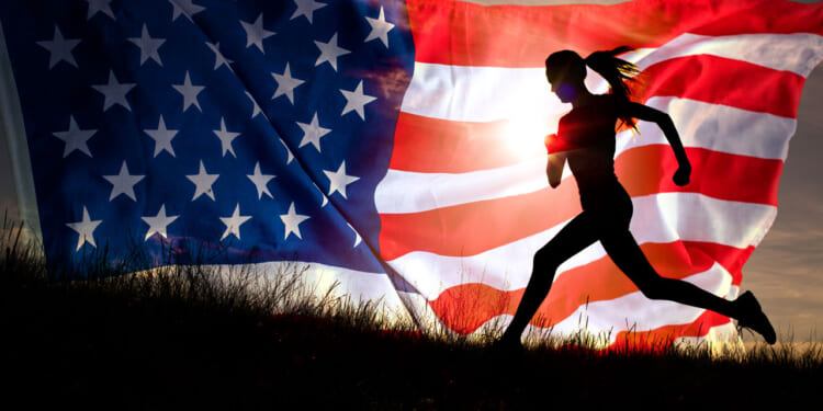 silhouette of a woman running up a small hill with graphic of American flag behind her, with sun shining through the flag's stripes.