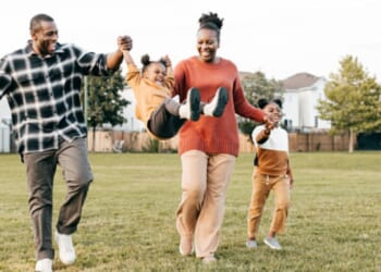 Parents play on a playing field with their young children.