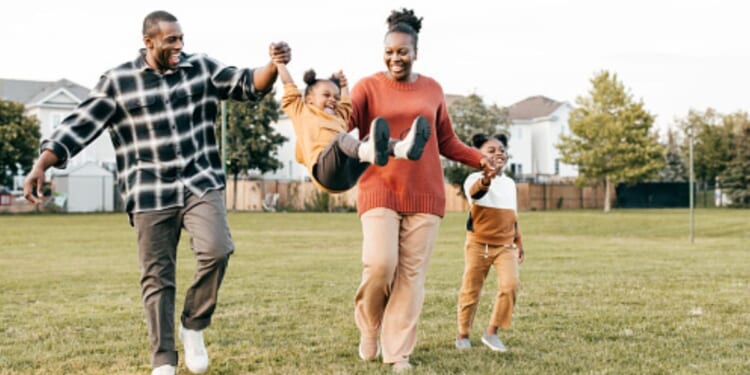Parents play on a playing field with their young children.