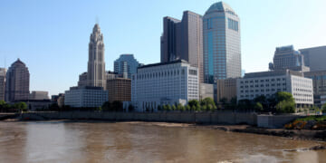 Downtown city skyline of Columbus, Ohio with river and blue sky in the background.