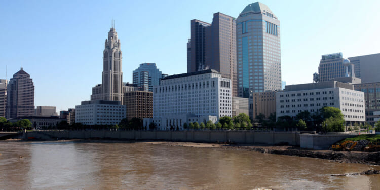 Downtown city skyline of Columbus, Ohio with river and blue sky in the background.