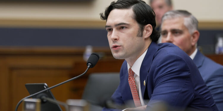 U.S. Rep. Brandon Gill leans forward in a blue suit and red tie.