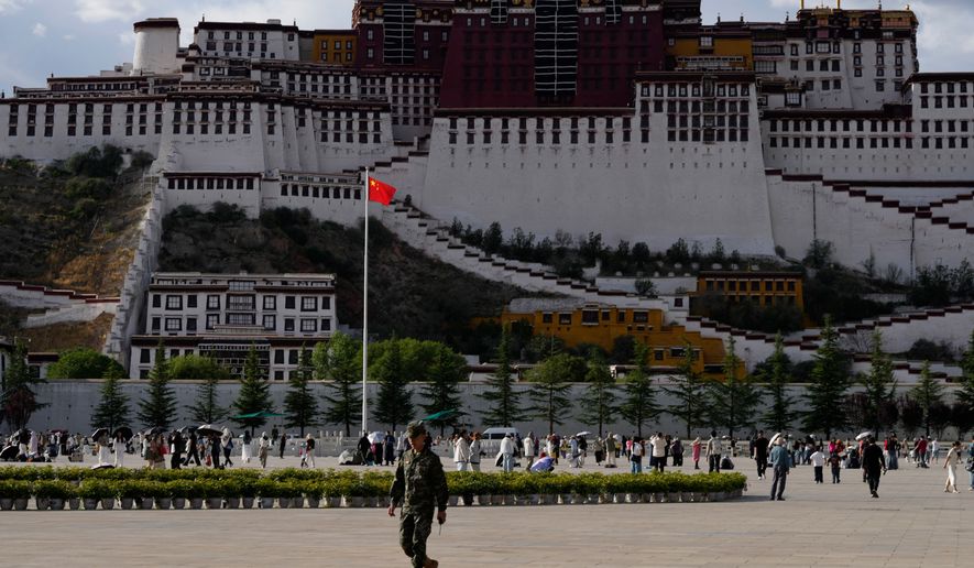 A soldier walks on a public square where a Chinese national flag hangs in front of the Potala Palace in western China's Tibet autonomous region on July 21, 2026, during a government-organized visit for foreign journalists.(AP Photo/Ng Han Guan)