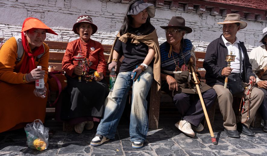 Qongqiu Quco, a 19-year-old student, sits with her relatives outside Jokhang Temple in Lhasa in western China's Tibet autonomous region on July 21, 2026, during a government- organized visit for foreign journalists. (AP Photo/Ng Han Guan)