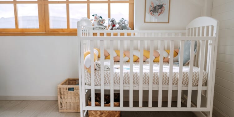 A baby crib in a modern cozy bedroom.