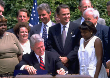Pres. Bill Clinton (C) signing controversial welfare reform bill in White House Rose Garden, w. former welfare recipients, VP Gore (2R), Sen. John Breaux (3L) & others. (Photo by Dirck Halstead/Getty Images)
