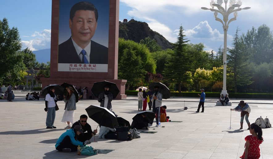 Tourists rest near a portrait of Chinese President Xi Jinping at a public square at the base of the Potala Palace in western China's Tibet autonomous region on July 21, 2026, during a government-organized visit for foreign journalists. (AP Photo/Ng Han Guan)