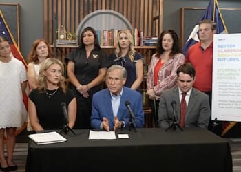 Texas Gov. Greg Abbott speaks at a table with microphones.