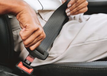 A close-up of someone putting on a seat belt.