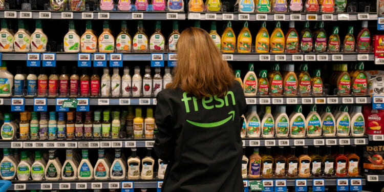 An employee arranges a salad dressing display at an Amazon Fresh grocery store on December 12, 2024 in Federal Way, Washington. Amazon recently held grand re-opening events for three redesigned Amazon Fresh stores in the Puget Sound region. (Photo by David Ryder/Getty Images)