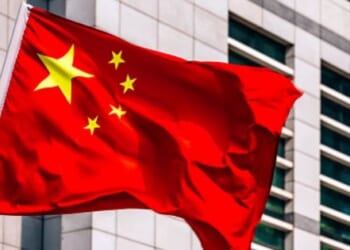 A Chinese flag flies near a large building.