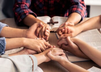 An image of young Christians holding hands and praying.