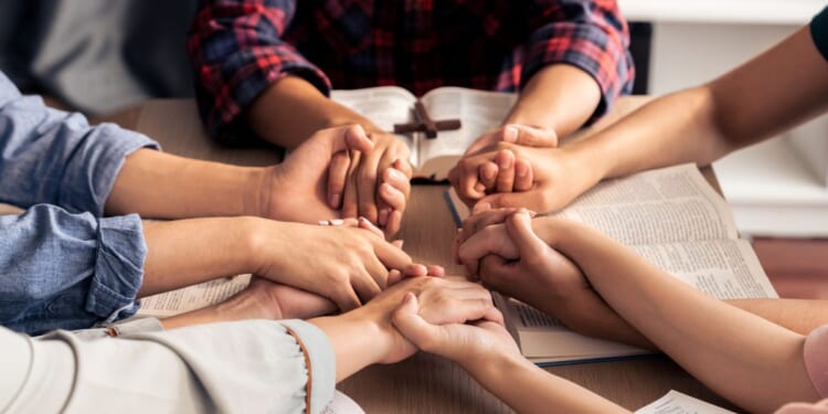 An image of young Christians holding hands and praying.