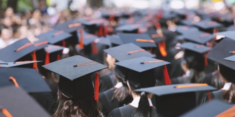 Students stand at a graduation ceremony.
