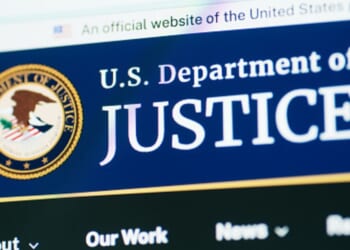 The Department of Justice website is pictured on a bright screen.