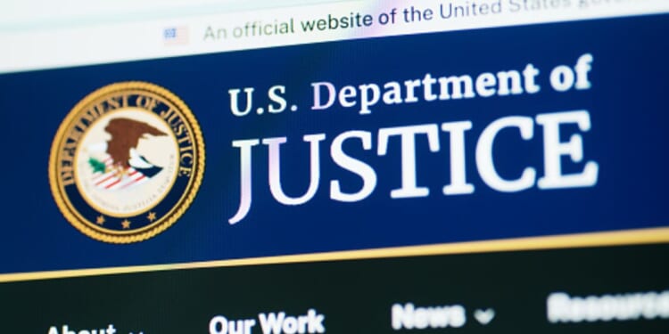 The Department of Justice website is pictured on a bright screen.