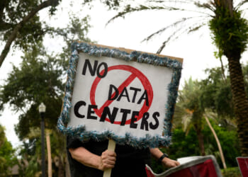 A person holds signs during a nationwide protest against AI data center expansion outside Peace Hall in New Port Richey, Florida on July 18, 2026. (Photo by Thomas Simonetti / AFP via Getty Images)